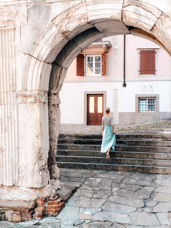 Frau läuft durch den Torbogen in Triest: Arco di Riccardo